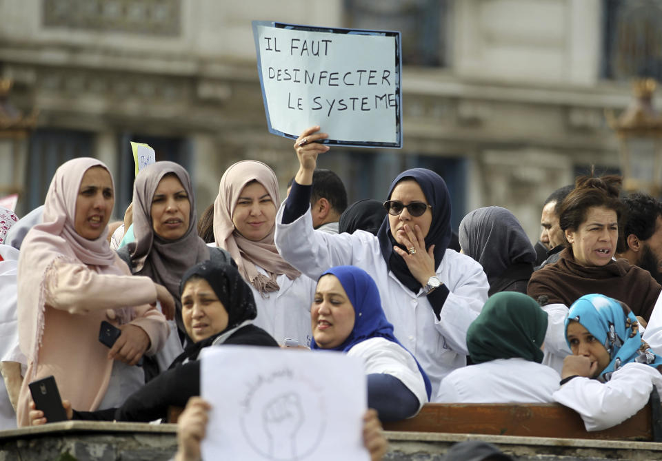 An algerians woman holds a placards that reads, 'we need to disinfected the system' during a protest in Algiers, Algeria, Tuesday, March 19, 2019. Thousands of students, doctors, dentists and veterinarians have marched in the Algerian capital to demand that President Abdelaziz Bouteflika step down. (AP Photo/Anis Belghoul)