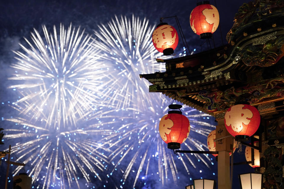 In this Tuesday, Dec. 3, 2019, photo, a lantern-covered float stands as fireworks light up the sky during the Chichibu Night Festival in Chichibu, Japan. Moving six towering floats up a hill and into the town center is the culminating moment of a Shinto festival that has evolved from a harvest thanksgiving into a once-a-year meeting between two local gods. (AP Photo/Toru Hanai)