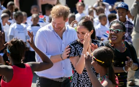 The Duke and Duchess of Sussex dance during a visit to Nyanga township in Cape Town in September - Credit: REX