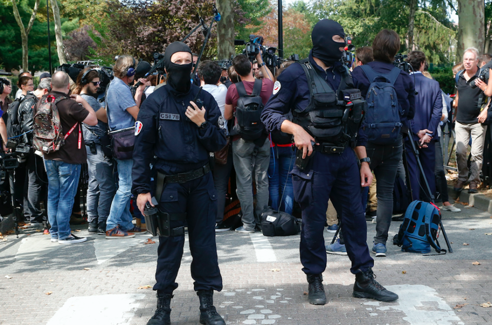 <em>Hooded police officers watch out while French Interior Minister Gerard Collomb answers reporters after a knife attack (AP)</em>