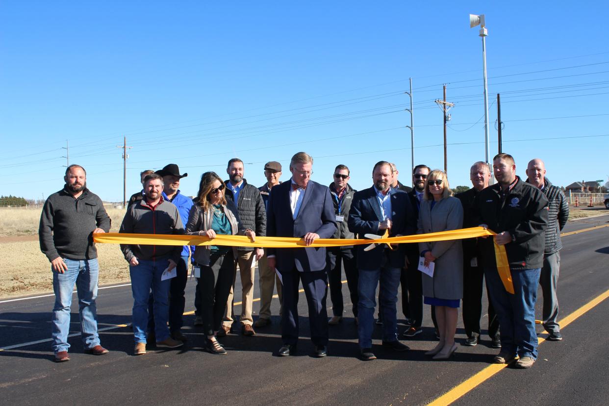 Lubbock County Commissioner Terence Kovar, holding scissors, and Lubbock County and Frenship ISD officials cut the ribbon on County Road 6900 between Upland Avenue and FM 179 Monday morning.