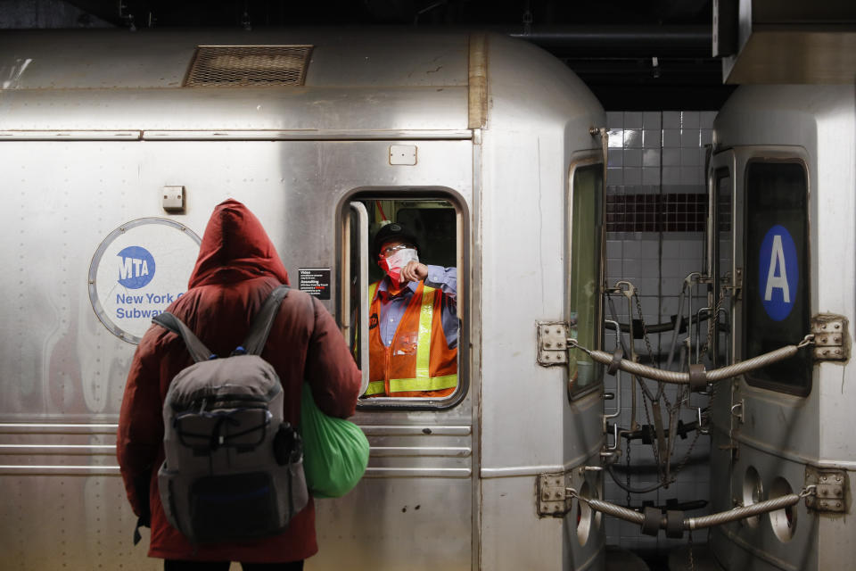 A MTA employee, wears a mask to protect against coronavirus, waits in the conductors area of a subway car as NYPD and MTA officers wake up sleeping passengers and direct them to the exits at the 207th Street A-train station, Thursday, April 30, 2020, in the Manhattan borough of New York. (AP Photo/John Minchillo)