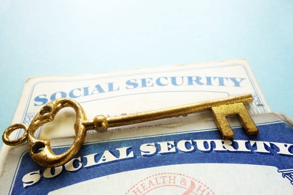 A golden key laying on top of two Social Security cards.