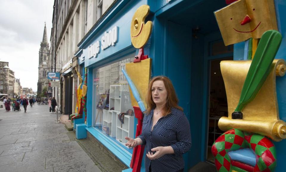 Shona McCarthy, the chief executive of the fringe, leans against a colourful shop front in Edinburgh