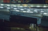 Two migrants cling to the roof of a freight truck as they arrive at the Eurotunnel terminal in the English city of Folkestone on July 31, 2015, after travelling through the Channel Tunnel from Calais, France