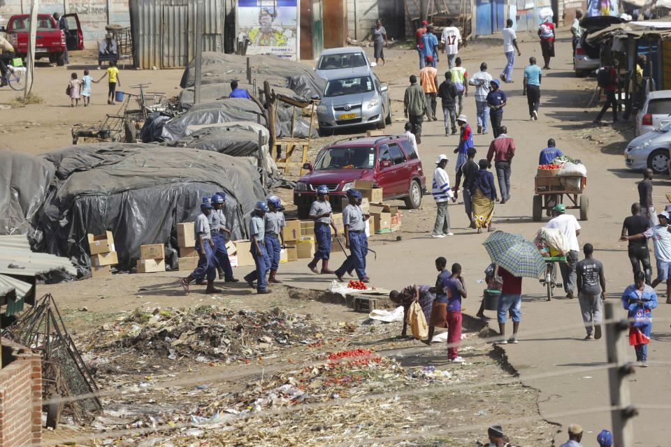 Zimbabwe riot police patrol the streets near a fruit and vegetable market full of people despite a lockdown in an effort to curb the spread of the coronavirus, in Harare, Zimbabwe, Tuesday April 7, 2020. (AP Photo/Tsvangirayi Mukwazhi)