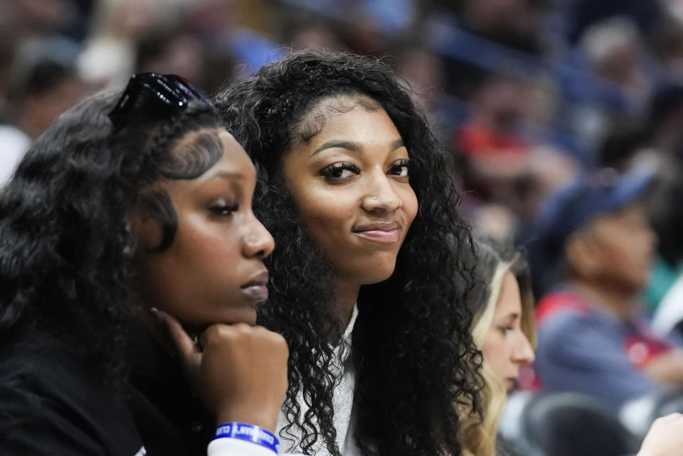 LSU basketball forward Angel Reese sits in her court side seat with teammate Amani Bartlett, left, in the second half of an NBA basketball game between the New Orleans Pelicans and the Orlando Magic in New Orleans, Wednesday, April 3, 2024. The Magic won 117-108. (AP Photo/Gerald Herbert)