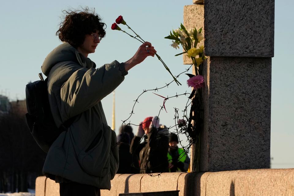 A woman places flowers as people pay tribute to Alexei Navalny at the Memorial to Victims of Political Repression in St. Petersburg, Russia, Sunday, Feb. 18, 2024. Russians across the vast country streamed to ad-hoc memorials with flowers and candles to pay tribute to Alexei Navalny, the most famous Russian opposition leader, and the Kremlin's fiercest critic. Russian officials reported that Navalny, 47, died in prison on Friday.