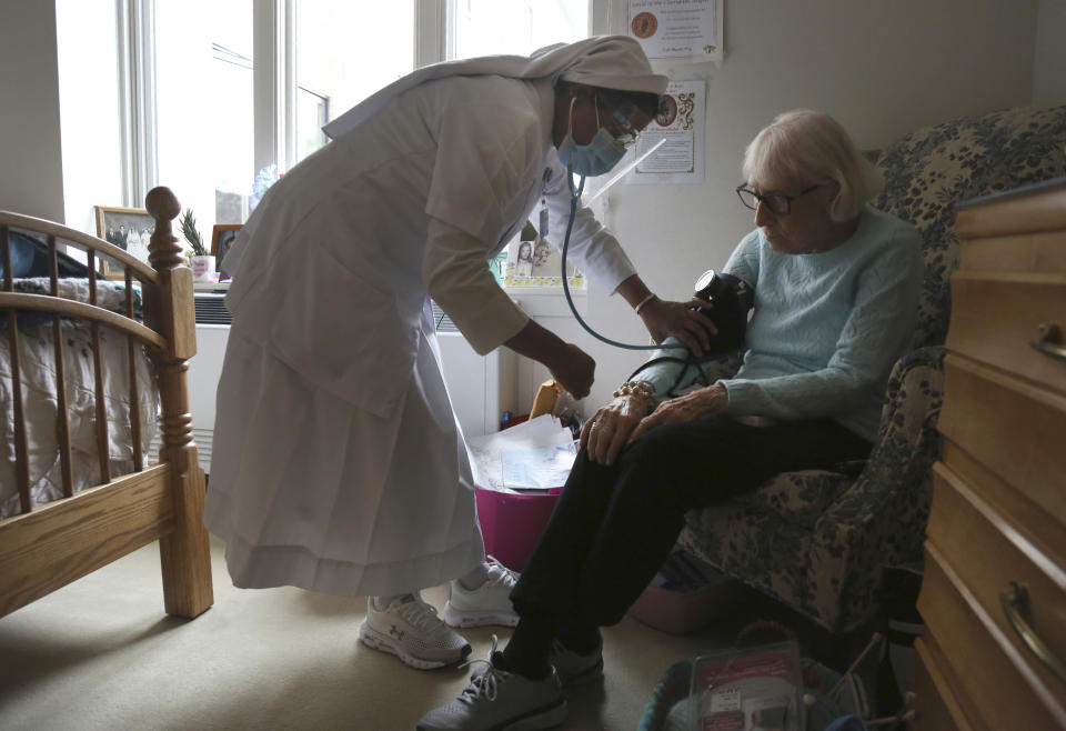 Sister Rose Nellivila checks the blood pressure of Lorraine Catney, a resident of Villa Angela at St. Anne Home nursing facility in Greensburg, Pa., Thursday, March 25, 2021. (AP Photo/Jessie Wardarski)