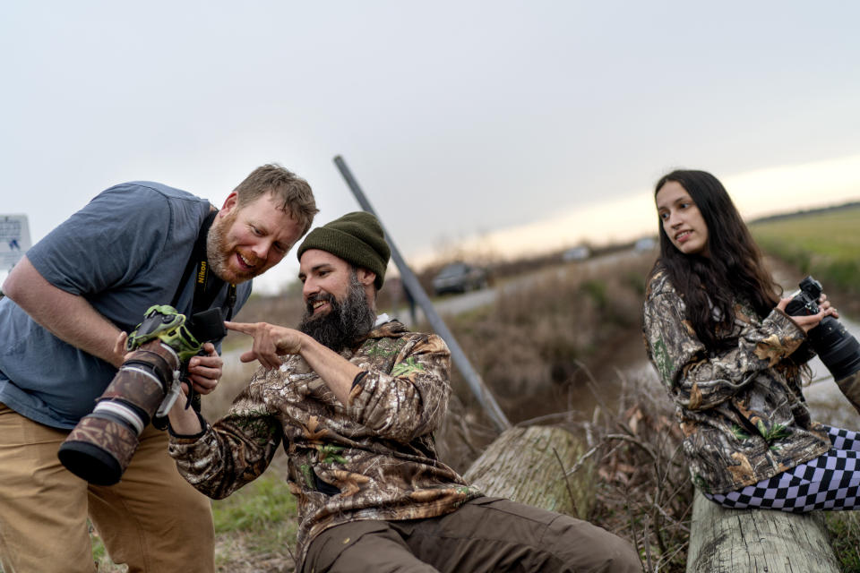 Ron Sutherland, left, a biologist with the Wildlands Network, reacts to a photo of a red wolf taken by James Ford, as they watch for wolves with fellow photographer and wildlife tour guide Aspen Stalls, right, on the Alligator River National Wildlife Refuge near Manns Harbor, N.C. Wednesday, March 22, 2023. (AP Photo/David Goldman)