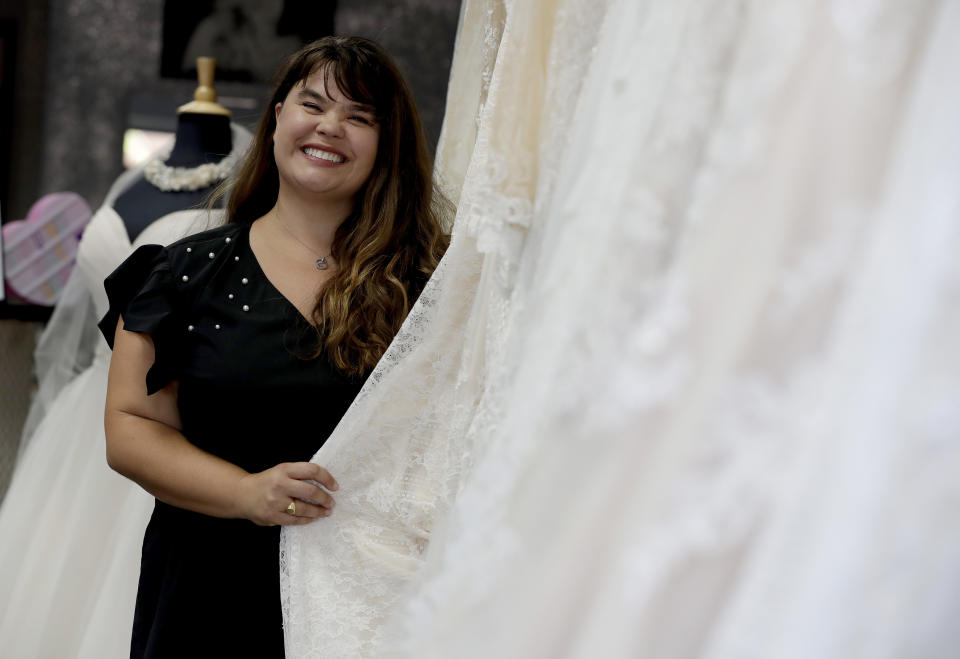 In this Friday, June 21, 2019, photo Ann Campeau, owner of Strut Bridal, stands in her shop in Tempe, Ariz. Cut-rate prices on websites that sell wedding dresses direct from China put pressure on Campeau, who owns four bridal shops in California and Arizona. She has had customers come in after seeing low-end gowns online and expecting to get a dress at a similar price. (AP Photo/Matt York)