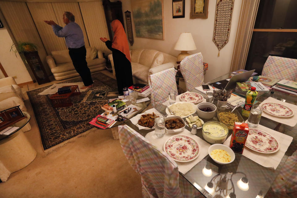 In this Tuesday, April 28, 2020, photo, Asghar Ali Khan and his wife Shaheen, participate in the evening prayer as the Iftar, the evening meal with which Muslims end their daily Ramadan fast at sunset, waits on the dining room table at their Wheeling,Ill., home. (AP Photo/Charles Rex Arbogast)