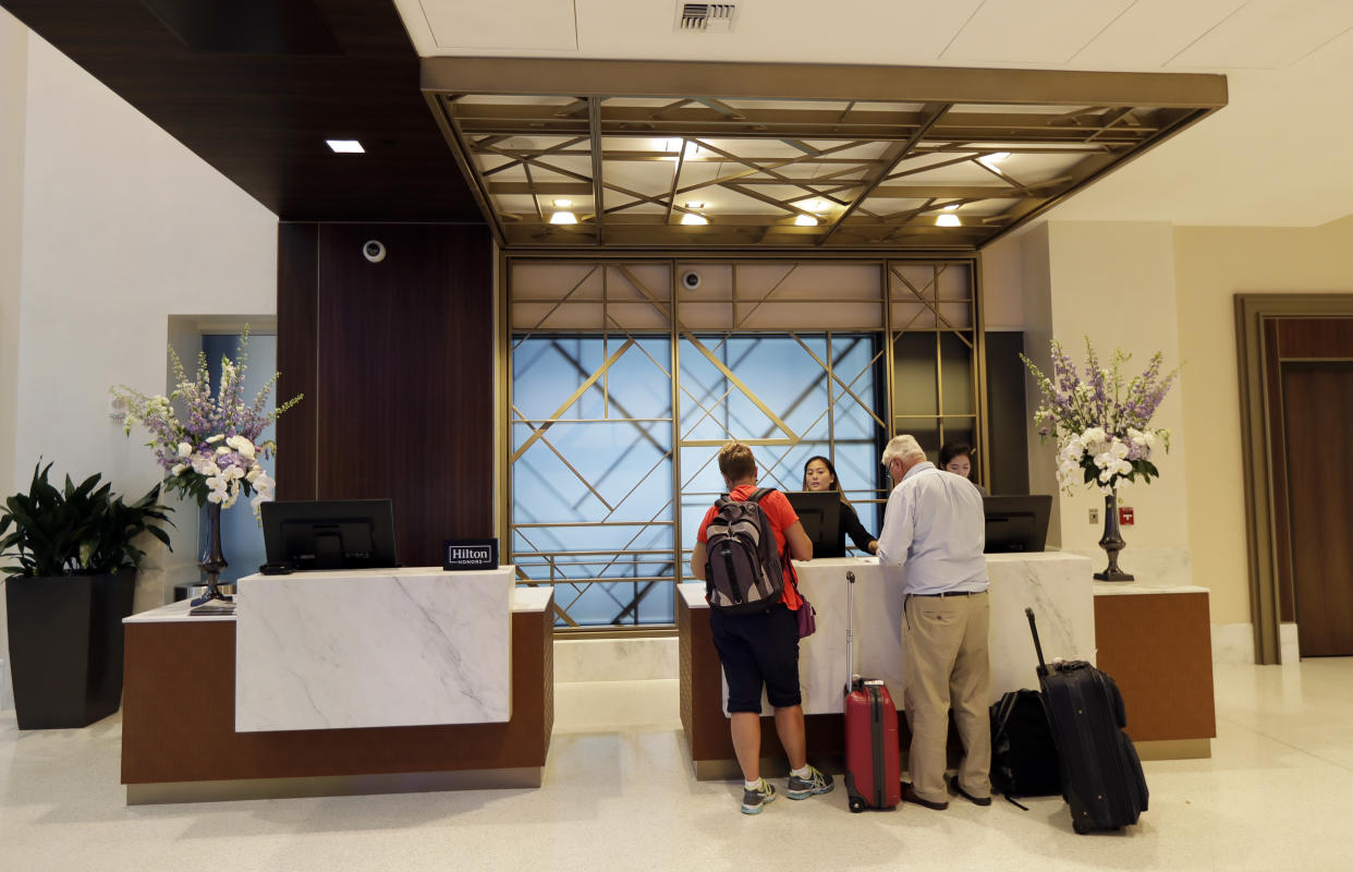 Guests with luggage stand at the check in desk at a Seattle hotel.