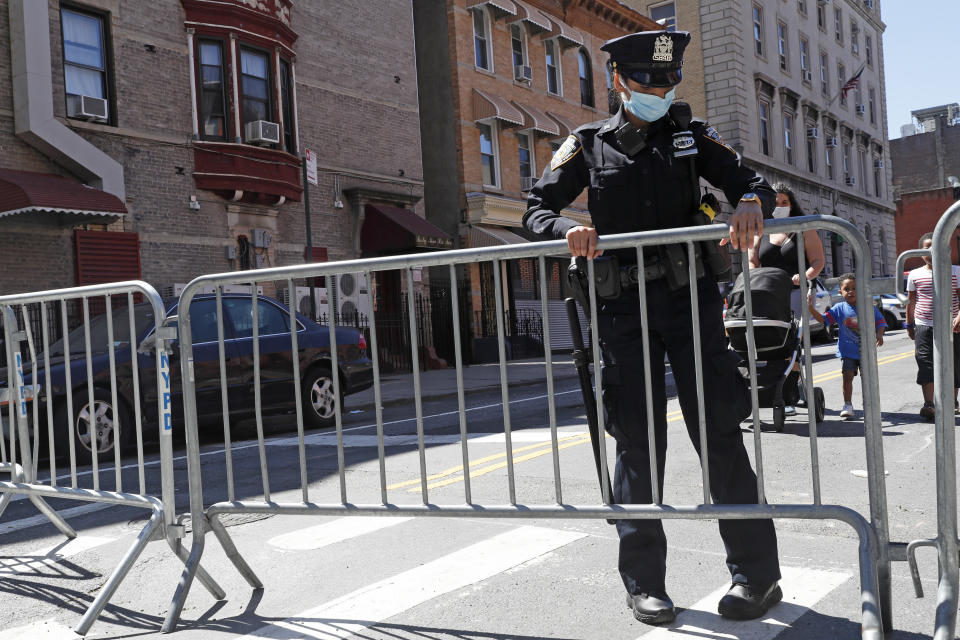 A police officer unlocks a barricade protecting a police precinct so a family can pass through, Sunday, May 31, 2020, in the Brooklyn borough of New York. The precinct is located near the Barclays Center, the site of large protests sparked by the death of George Floyd, which grew violent Saturday night. Floyd died on Memorial Day in Minnesota. (AP Photo/Kathy Willens)
