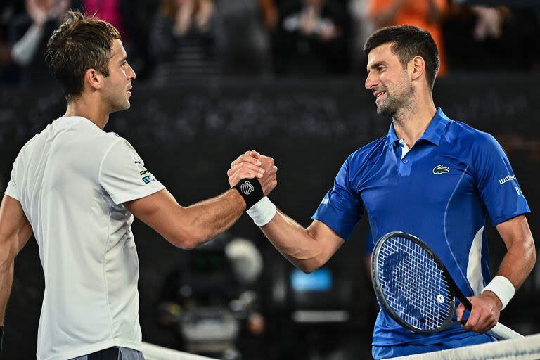 Serbia's Novak Djokovic (R) speaks with Argentina's Tomas Etcheverry after victory during their men's singles match on day six of the Australian Open tennis tournament in Melbourne on January 19, 2024. (Photo by Lillian SUWANRUMPHA / AFP) / -- IMAGE RESTRICTED TO EDITORIAL USE - STRICTLY NO COMMERCIAL USE --