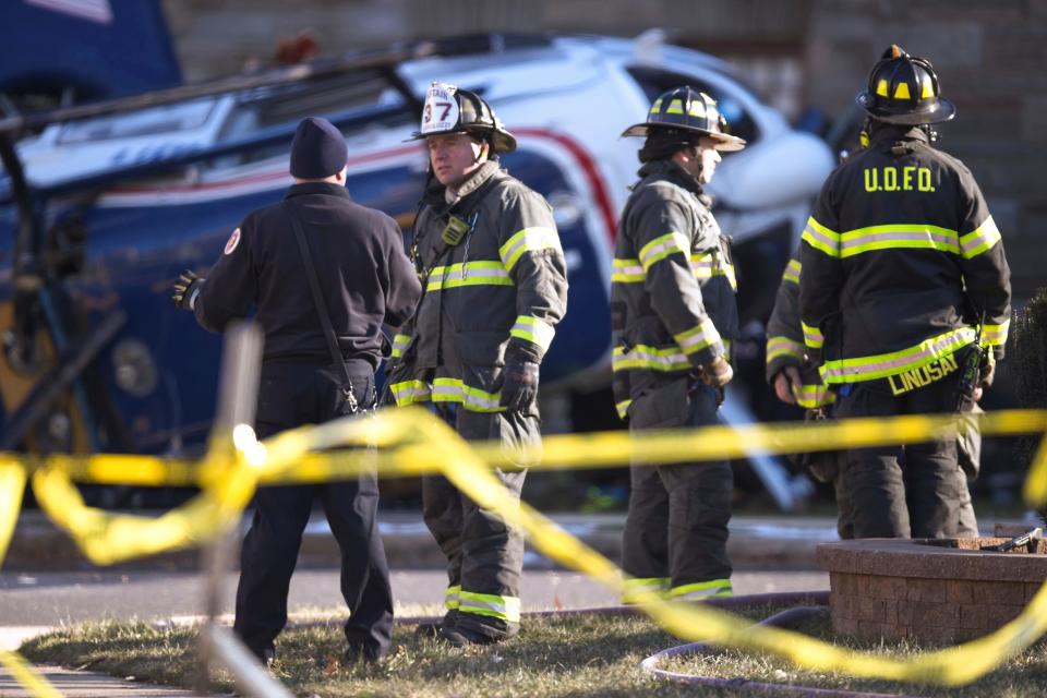 Firefighters gather at the scene after a medical helicopter crashed in the Drexel Hill section of Upper Darby Township in Delaware County, Pa., on Tuesday, Jan. 11, 2022.