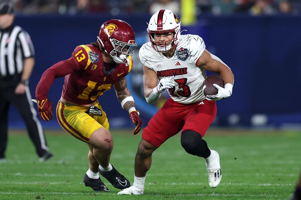 Isaac Guerendo #23 of the Louisville Cardinals rushes the ball past the defense of Mason Cobb #13 of the USC Trojans during the first half of the DIRECTV Holiday Bowl at Petco Park on December 27, 2023 in San Diego, California.