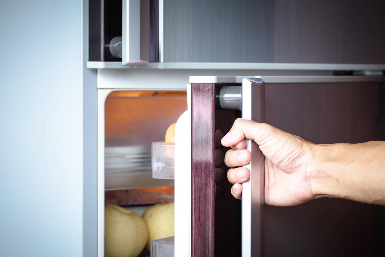 hand a young man is opening a refrigerator door