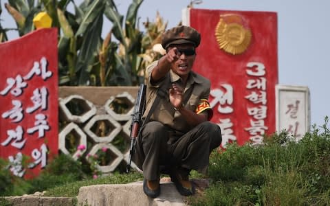 A North Korean soldier reacts as tourists pass by in a boat near the North Korean town of Sinuiju, opposite the Chinese border city of Dandong,  - Credit: GREG BAKER/AFP