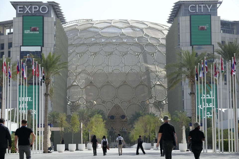 People walk near the Al Wasl Dome at the Expo City ahead of the COP28 U.N. Climate Summit, Tuesday, Nov. 28, 2023, in Dubai, United Arab Emirates. (AP Photo/Peter Dejong)