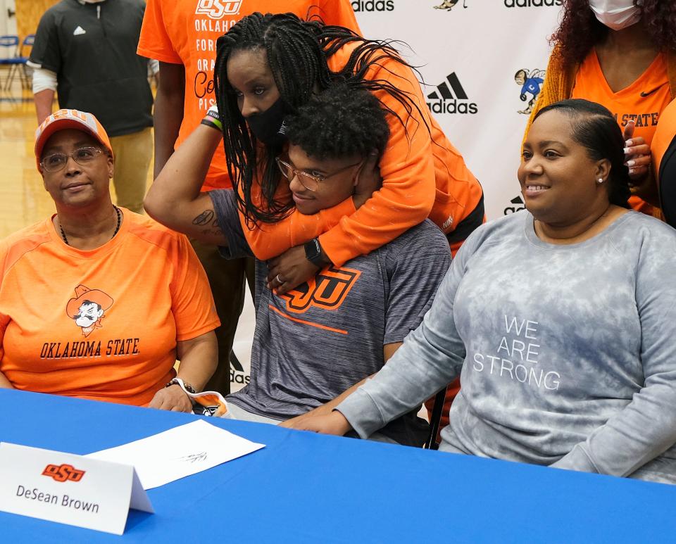DeSean Brown's aunt, Heather Crutchfield hugs him. Next to him are his grandmother, Lisa Brown, left, and mother, Lawauna Brown, at Choctaw High School, where he signed a letter of intent with OSU on national signing day, Wednesday, December 15, 2021. 