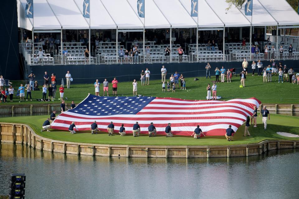 A flag is unfurled on the 17th green during the 2020 Players Championship Military Appreciation Day ceremony.