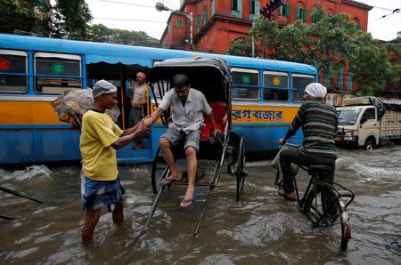 A rickshaw puller helps a passenger get down at a water-logged street after heavy rain in Kolkata, India, June 26, 2018. REUTERS/Rupak De Chowdhuri