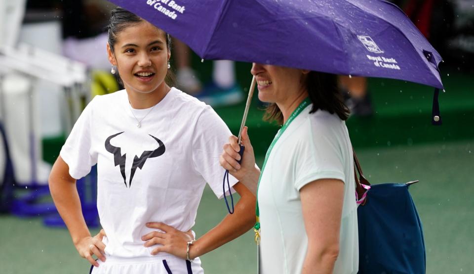 Emma Raducanu takes shelter from the rain ahead of a training session  - Adam Davy/PA Wire