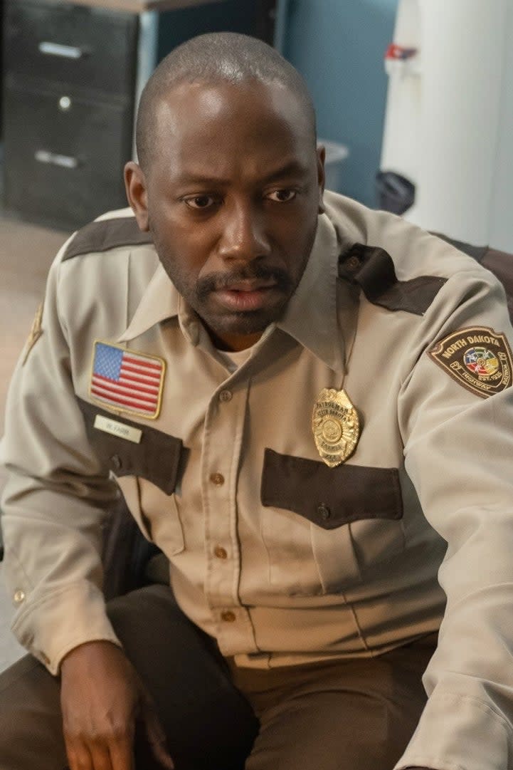 Two sheriff's deputies, Olmstead and another unidentified deputy, are seated at a desk looking intently at a computer screen in a police station