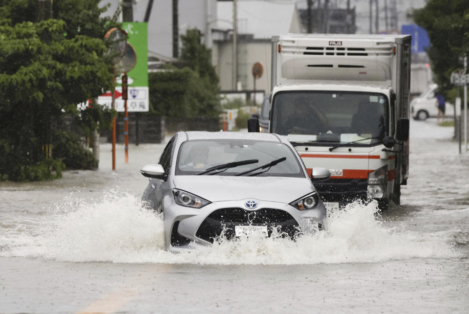 Vehicles shift through a flooded street in Kurume, Fukuoka prefecture, southern Japan Monday, July 10, 2023. Torrential rain is pounding southwestern Japan, triggering floods and mudslides Monday as weather officials issued emergency heavy rain warning in parts of on the southern most main island of Kyushu. (Kyodo News via AP)