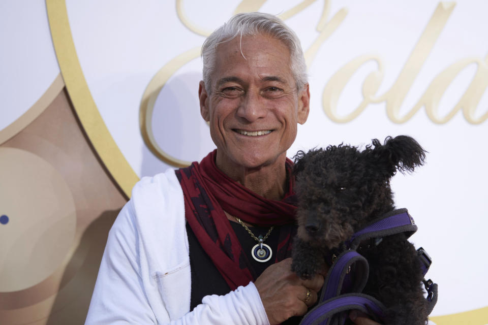 Greg Louganis holding a black dog.