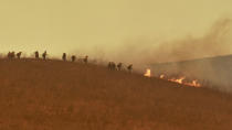 In this photo provided by the Santa Barbara County Fire Department, a hand crew works on a hill to extinguish a fire Tuesday, Oct. 12, 2021, in Goleta, Calif. (Mike Eliason/Santa Barbara County Fire Department via AP)