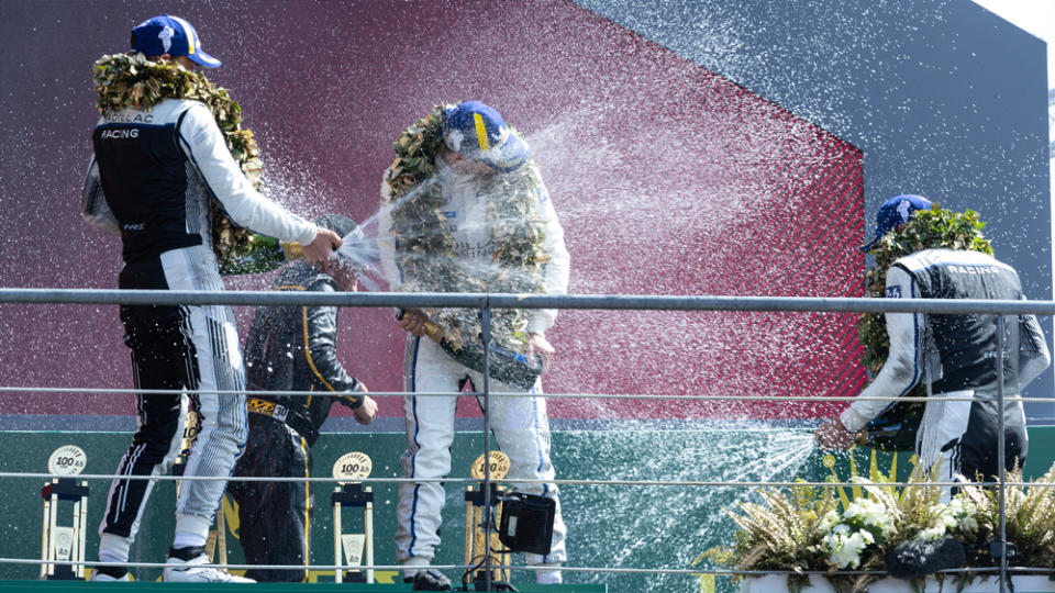 Racers Earl Bamber, Alex Lynn, and Richard Westbrook celebrate their podium result in the Hypercar class at the 2023 24 Hours of Le Mans.