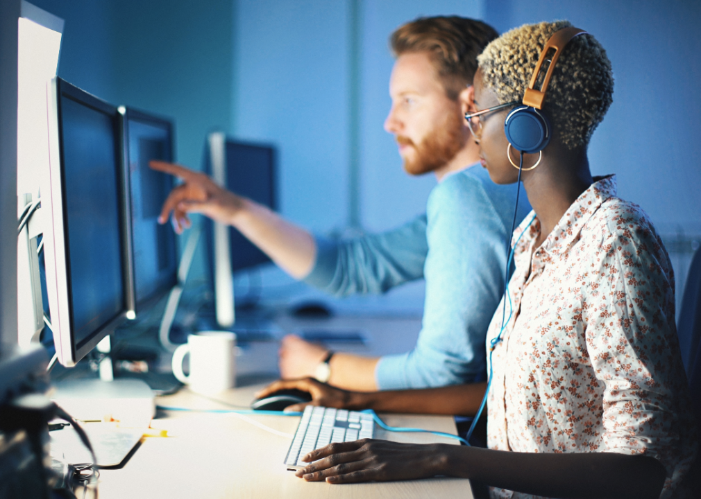 Two people work at desktop computers.