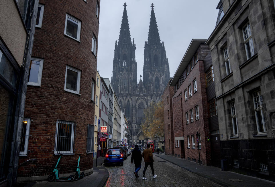 Two men walk along a street near the Cologne Cathedral in Cologne, Germany, Wednesday, Nov. 30, 2022. An unprecedented crisis of confidence is shaking the Archdiocese of Cologne. Catholic believers have protested their deeply divisive bishop and are leaving in droves over allegations that he may have covered up clergy sexual abuse reports. (AP Photo/Michael Probst)