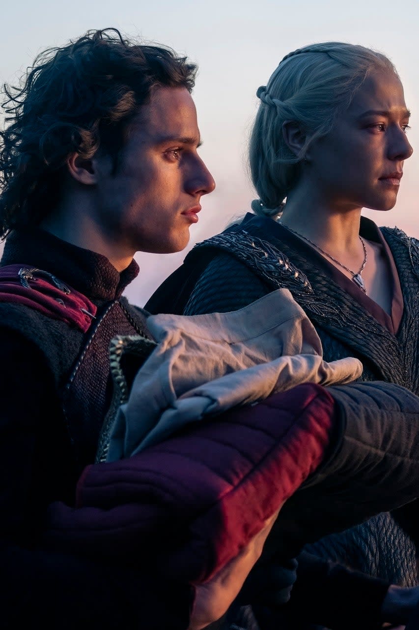 Harry Collett, Emma D’Arcy, Oscar Eskinazi in medieval clothing looking at a sunset in a scene from 