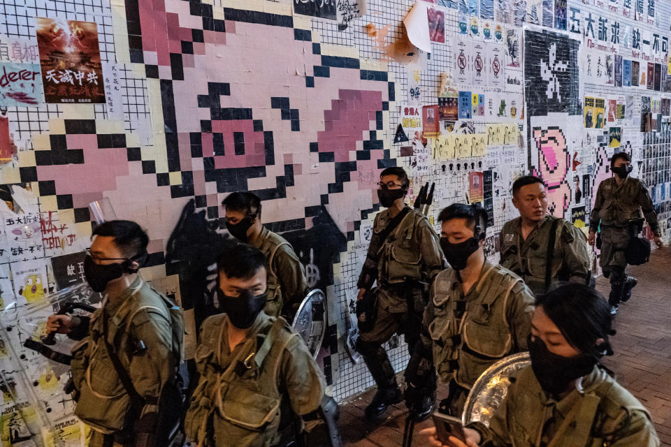 HONG KONG, CHINA - October 3: Riot police patrol in front of a Lennon wall with the LIHKG Pig mascot ouside Tai Koo MTR station on October 3, 2019 in Hong Kong, China. On October 1, pro-democracy protesters marked the 70th anniversary of the founding of the People's Republic of China in Hong Kong with mass demonstrations across Hong Kong. The day was marred by the first injuries caused from police use of live ammunition with one student protester shot in the chest in the Tsuen Wan district. The city remains on edge with the anti-government movement entering its fourth month. Protesters in Hong Kong continue to call for Chief Executive Carrie Lam to meet their remaining demands since the controversial extradition bill was withdrawn, which includes an independent inquiry into police brutality, the retraction of the word "riot" to describe the rallies, and genuine universal suffrage, as the territory faces a leadership crisis. (Photo by Anthony Kwan/Getty Images)