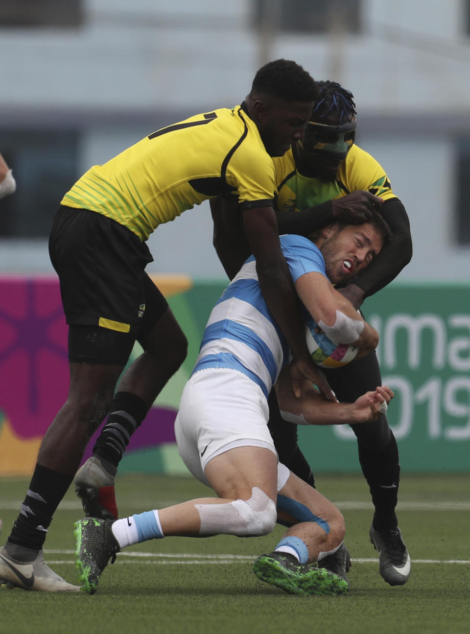 Franco Sabato of Argentina, center, is tackled by Mikel Facey, left, and Oshane Edie of Jamaica during rugby seven match at the Pan Am Games in Lima, Peru, Friday, July 26, 2019. Argentina won the match 52-0. (AP Photo/Juan Karita)