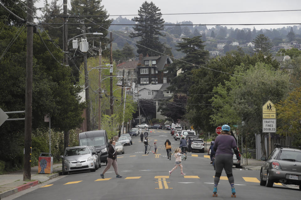 People walk and ride bicycles and scooters on 42nd Street in Oakland, California. The road has been closed to traffic to make it easier for people to socially distance. (Photo: AP Photo/Jeff Chiu)