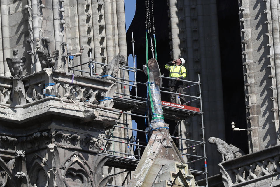 A worker prepares to remove a statue from the damaged Notre Dame cathedral, in Paris, Friday, April 19, 2019. Rebuilding Notre Dame, the 800-year-old Paris cathedral devastated by fire this week, will cost billions of dollars as architects, historians and artisans work to preserve the medieval landmark. (AP Photo/Thibault Camus)