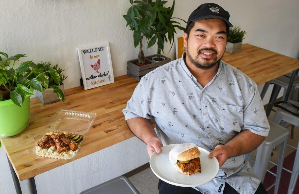 Long Nguyen, owner of Pacific Fried Chicken, sits with a hot chicken sandwich in his now-closed restaurant. The business is still doing pop-ups occasionally.