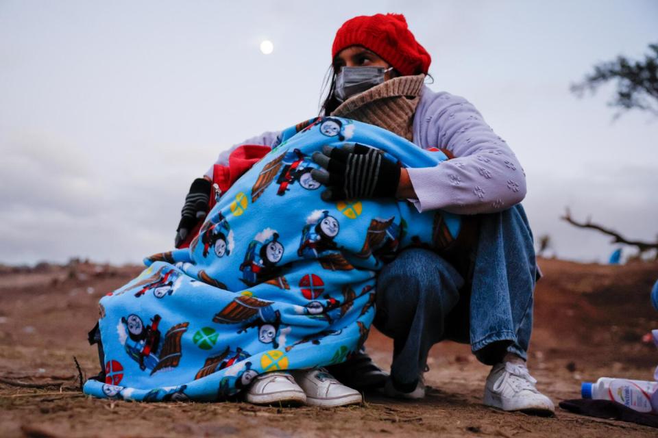 A woman wraps her daughter in a blanket to protect from the cold.