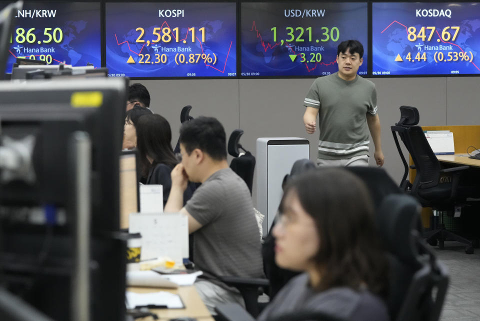 A currency trader passes by screens showing the Korea Composite Stock Price Index (KOSPI), top center left, and and the foreign exchange rate between U.S. dollar and South Korean won, top center right, at the foreign exchange dealing room of the KEB Hana Bank headquarters in Seoul, South Korea, Tuesday, May 30, 2023. Asian shares were mixed in directionless trading Tuesday following a U.S. holiday, as optimism about a deal on the U.S. debt mixed with worries about the regional economy. (AP Photo/Ahn Young-joon)