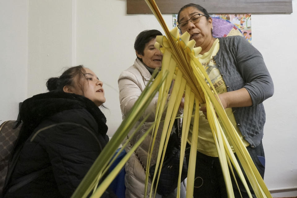 Isabel Tenorio, right, teaches how to weave palm fronds into elaborate designs to Kari Mendoza, left, and her mother, Maria Teresa Mendoza, at the Church of the Incarnation in anticipation of Palm Sunday in Minneapolis on Wednesday, March 29, 2023. The Mendozas were eager to learn this craft, popular in their native Mexico, because “it’s a blessing to have a little blessed palm,” Kari Mendoza said. (AP Photo/Giovanna Dell’Orto)