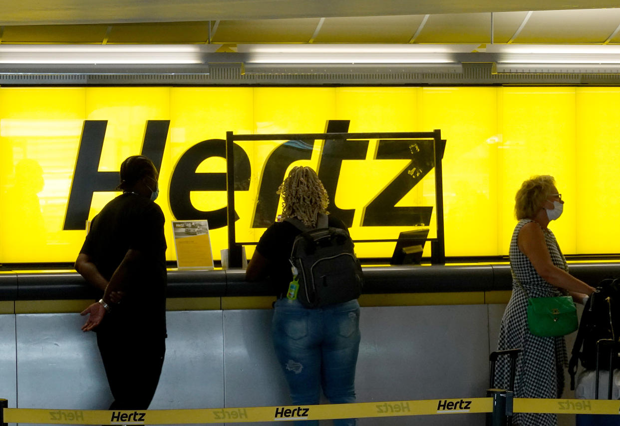 FORT LAUDERDALE, FLORIDA - OCTOBER 25: People stand at a Hertz car rental counter in the Fort Lauderdale-Hollywood International Airport on October 25, 2021 in Miami, Florida. Hertz announced that it ordered 100,000 Teslas as the company is emerging from bankruptcy. (Photo by Joe Raedle/Getty Images)