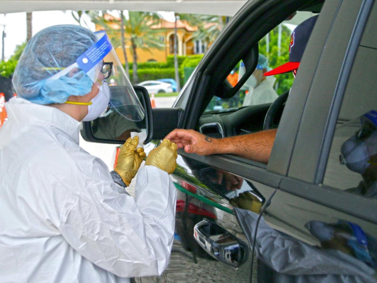 A man is tested by a health worker at a coronavirus antibody test drive-through site in Bal Harbour, Florida, US, 13 May 2020: David Santiago/Miami Herald via AP