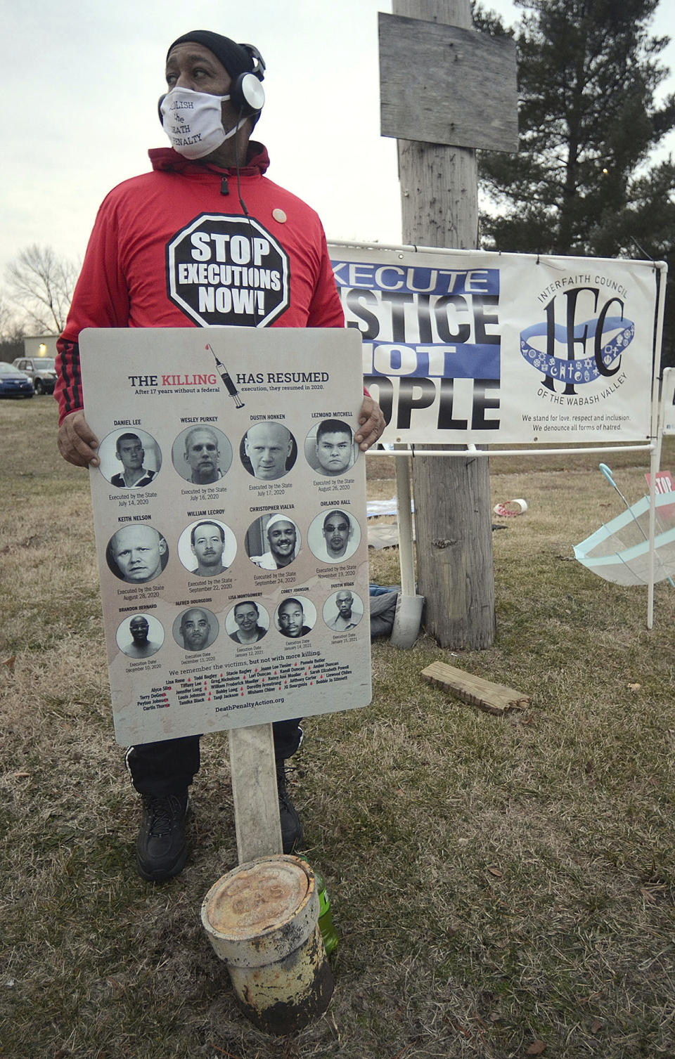 At a protest of the execution of Corey Johnson, Thursday, Jan. 14, 2021, near the Federal Correctional Complex in Terre Haute, Ind., Charles Keith, of Canton, Ohio, holds a sign with all of the mugshots of the 10 men and one woman who have been executed by the federal government since July 14, 2020. (Joseph C. Garza/The Tribune-Star via AP)