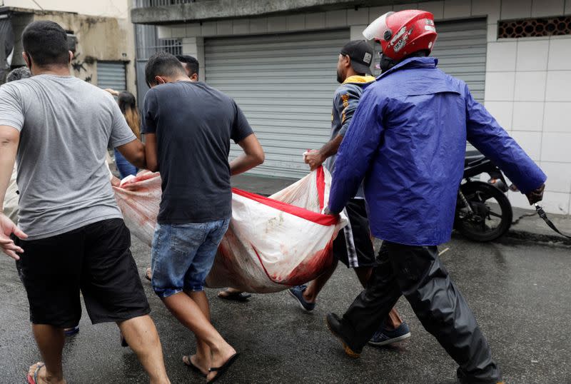 Residents carry a dead body after a police operation against drug gangs in Rio de Janeiro
