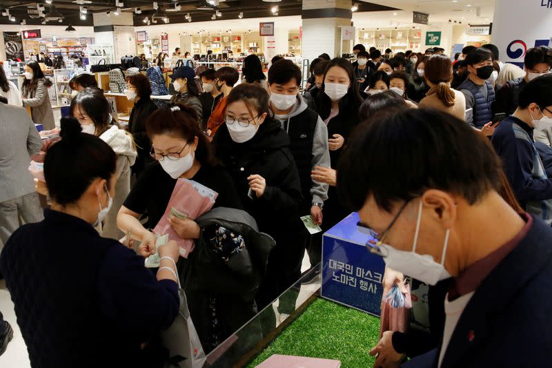 People wearing masks to prevent contracting the coronavirus wait in line to buy masks at a department store in Seoul