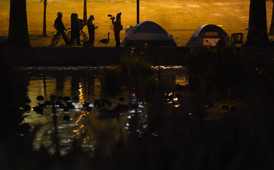 Members of the media interview demonstrators outside their tents in the Echo Park Lake homeless encampment in Los Angeles late Wednesday, March 24, 2021. (AP Photo/Damian Dovarganes)